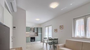 En moderne lejlighed med spiseområde, tekøkken og sofa.