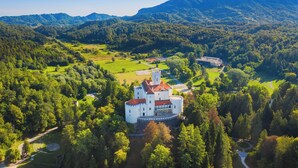 An aerial view of a castle surrounded by lush greenery and mountains. - Trakoscan Castle View Pool House /w Private Spa (Bednja)