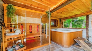 A wooden cabin interior with a glass-enclosed sauna, wooden shelves with mugs, and a stone wall. - Trakoscan Castle View Pool House /w Private Spa (Bednja)