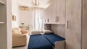 A compact bedroom with a bed, a sofa, and a wardrobe.