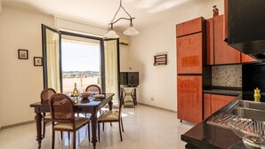 A dining area with a table and chairs, a kitchen with wooden cabinets, and a view through an open door.