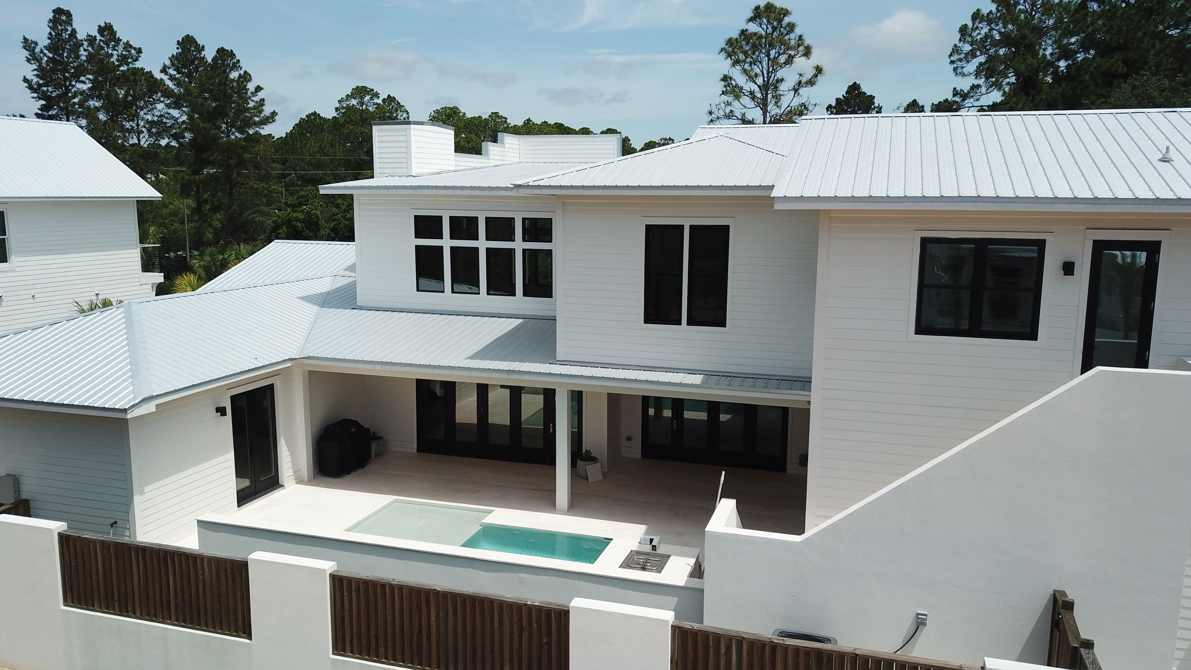 Une maison moderne à deux étages, dotée d’un patio couvert et d’une piscine.