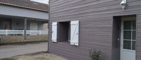 Un edificio de dos pisos con entrada de grava y valla blanca.