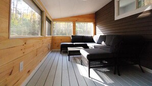 Mökin sisätilat: puulattia, sohva ja ikkuna, josta avautuu näkymä metsään.