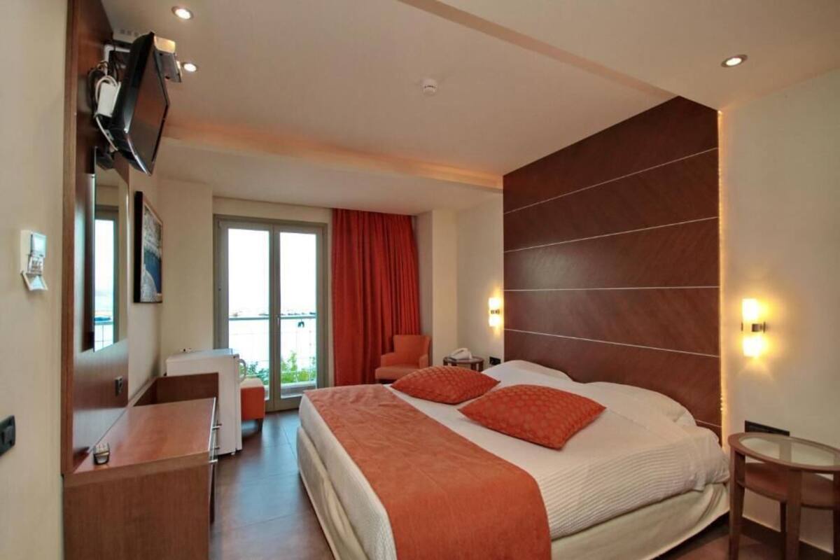 Une chambre d’hôtel avec un grand lit, un bureau, une chaise, un téléviseur fixé au mur et une vue sur l’extérieur.