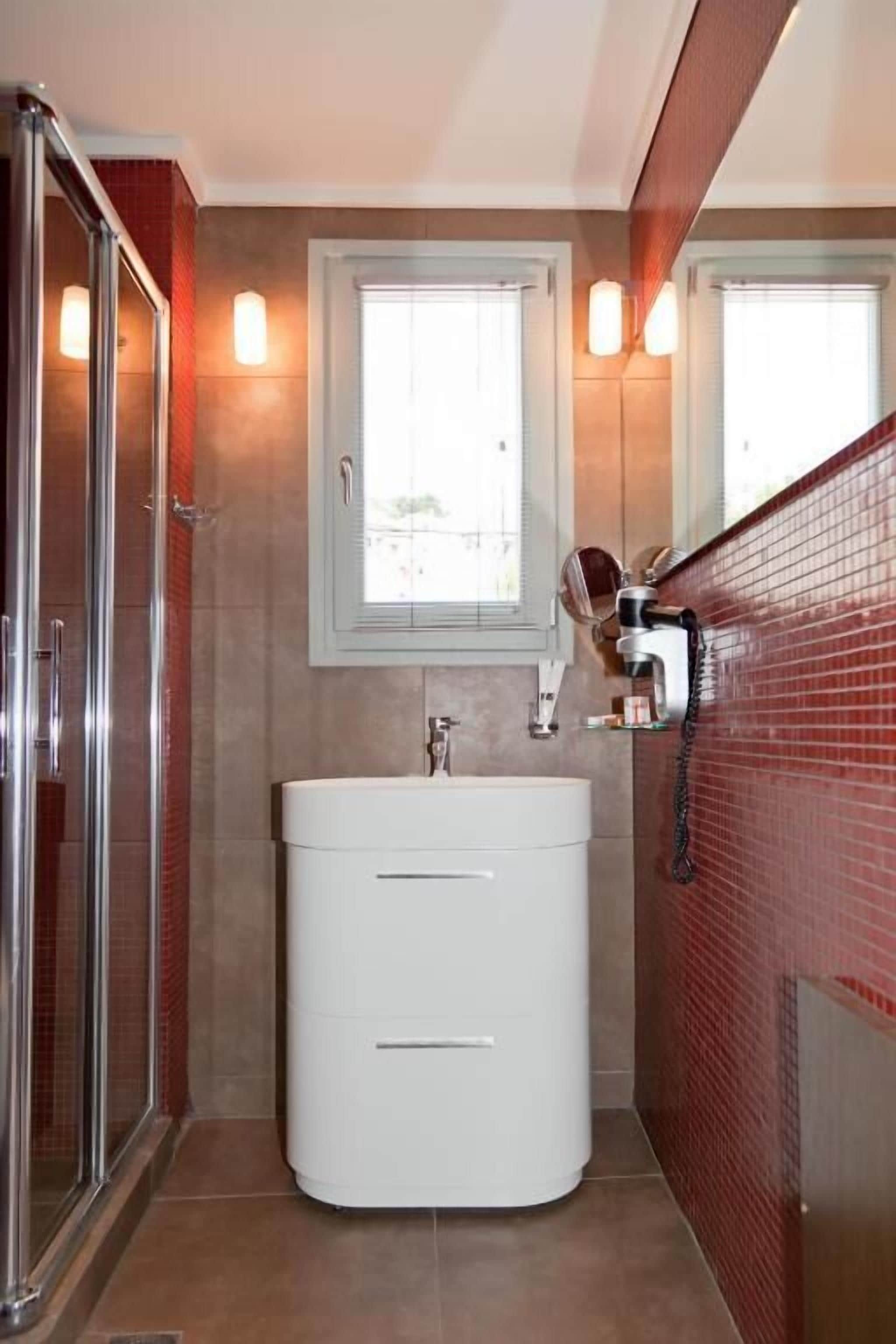 Een moderne badkamer met een douchecabine van glas, een wit wastafelmeubel en rode wandtegels.