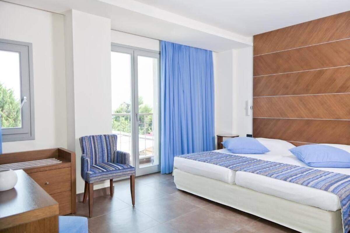 Une chambre d’hôtel avec un lit, une chaise, un bureau et une vue sur l’extérieur grâce à une porte coulissante.