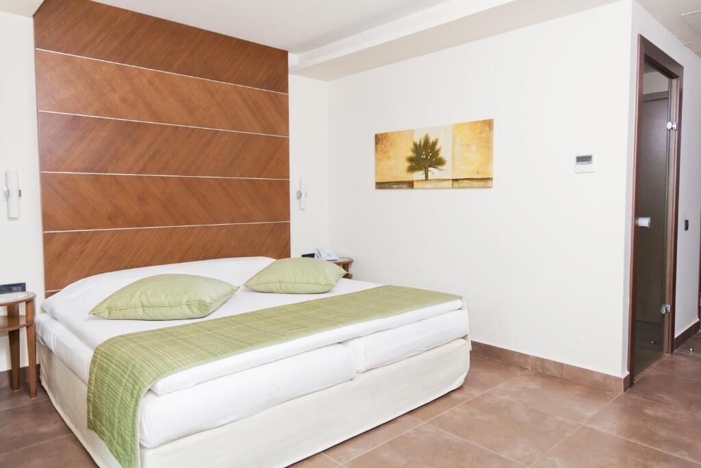 A modern bedroom with a large bed, a wooden headboard, and a painting on the wall.