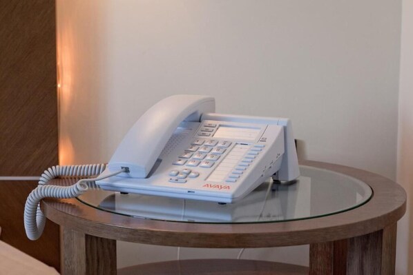 A white telephone on a glass table in a room. - Astros Beach Hotel (Paralio Astros)