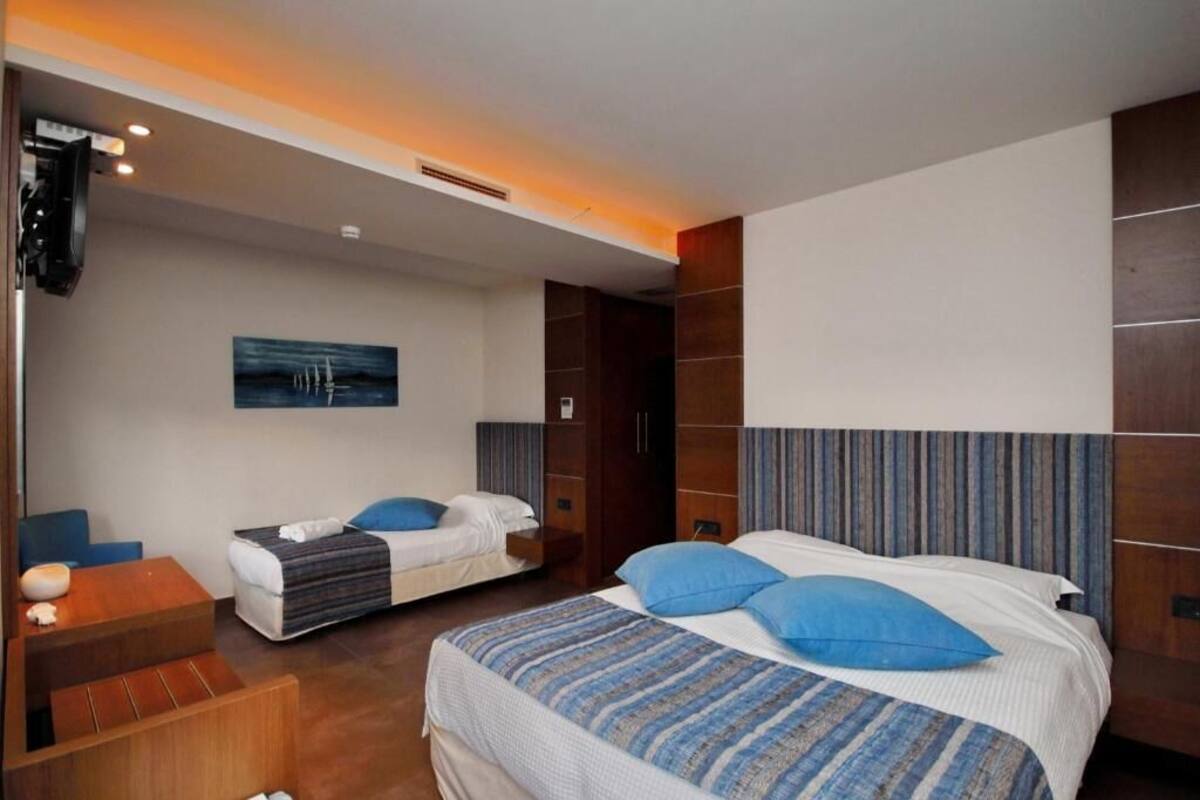 Une chambre d’hôtel avec deux lits, une télévision, un tableau et une armoire en bois.