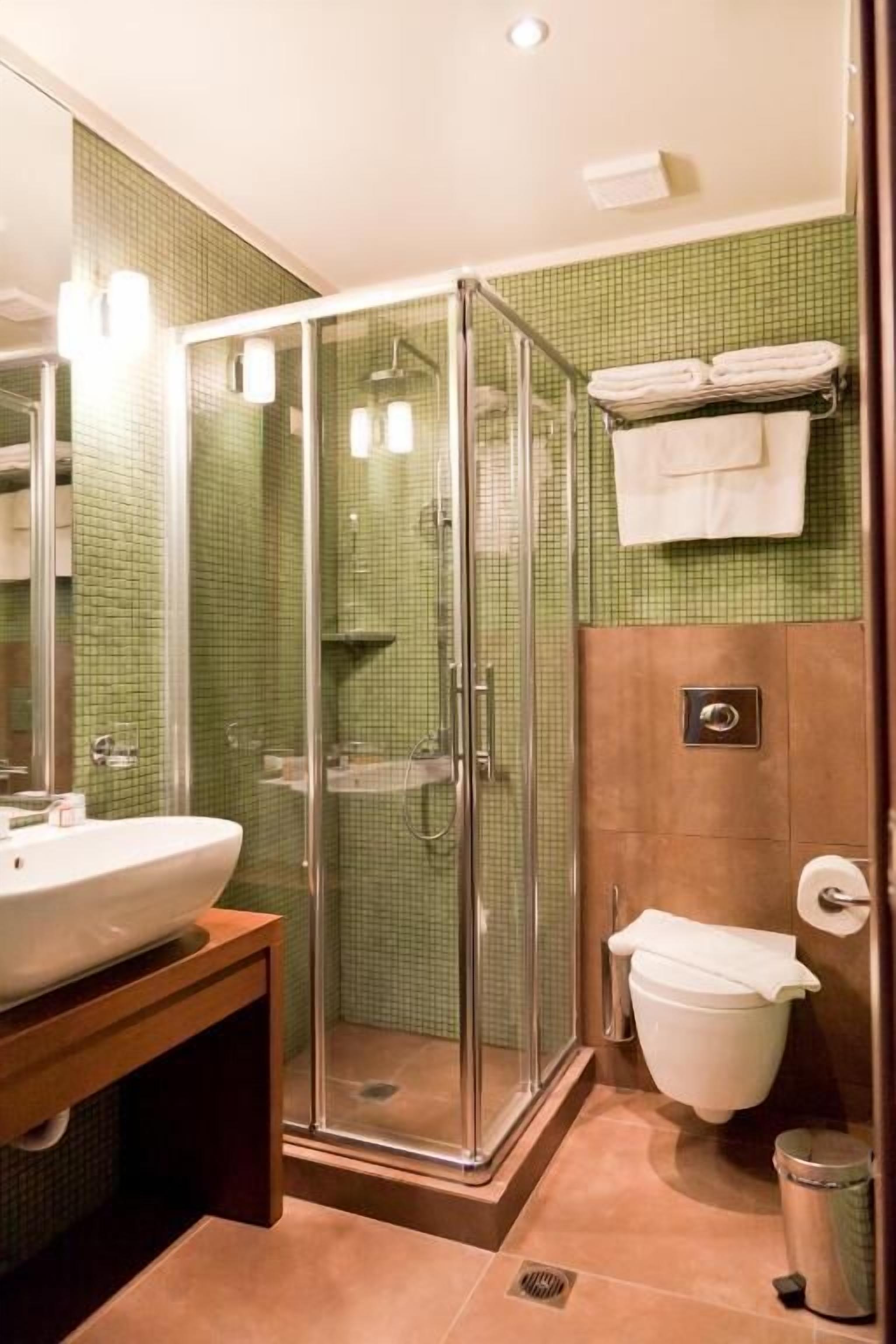 Un baño con ducha de vidrio, un lavamanos y un inodoro.