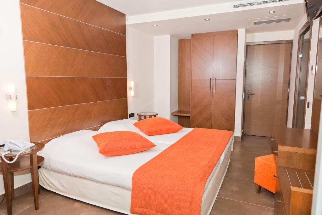 Habitació d'hotel amb llit, armari de fusta, taula petita i cadira.