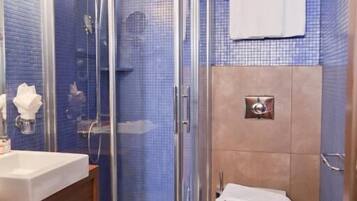 A bathroom with a glass-enclosed shower, a sink, a toilet, and a towel rack.
