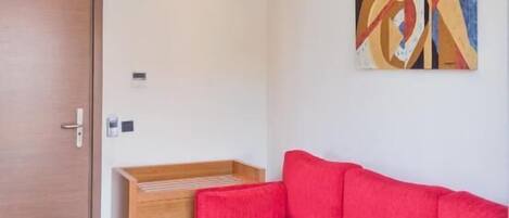 Een moderne woonkamer met een rode bank, een houten salontafel en een bijzettafeltje van hout.