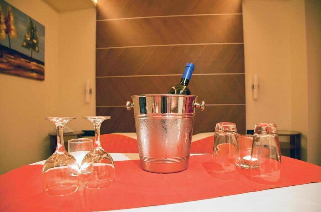 Une table sur laquelle se trouve un seau métallique contenant une bouteille, entourée de verres à vin vides.