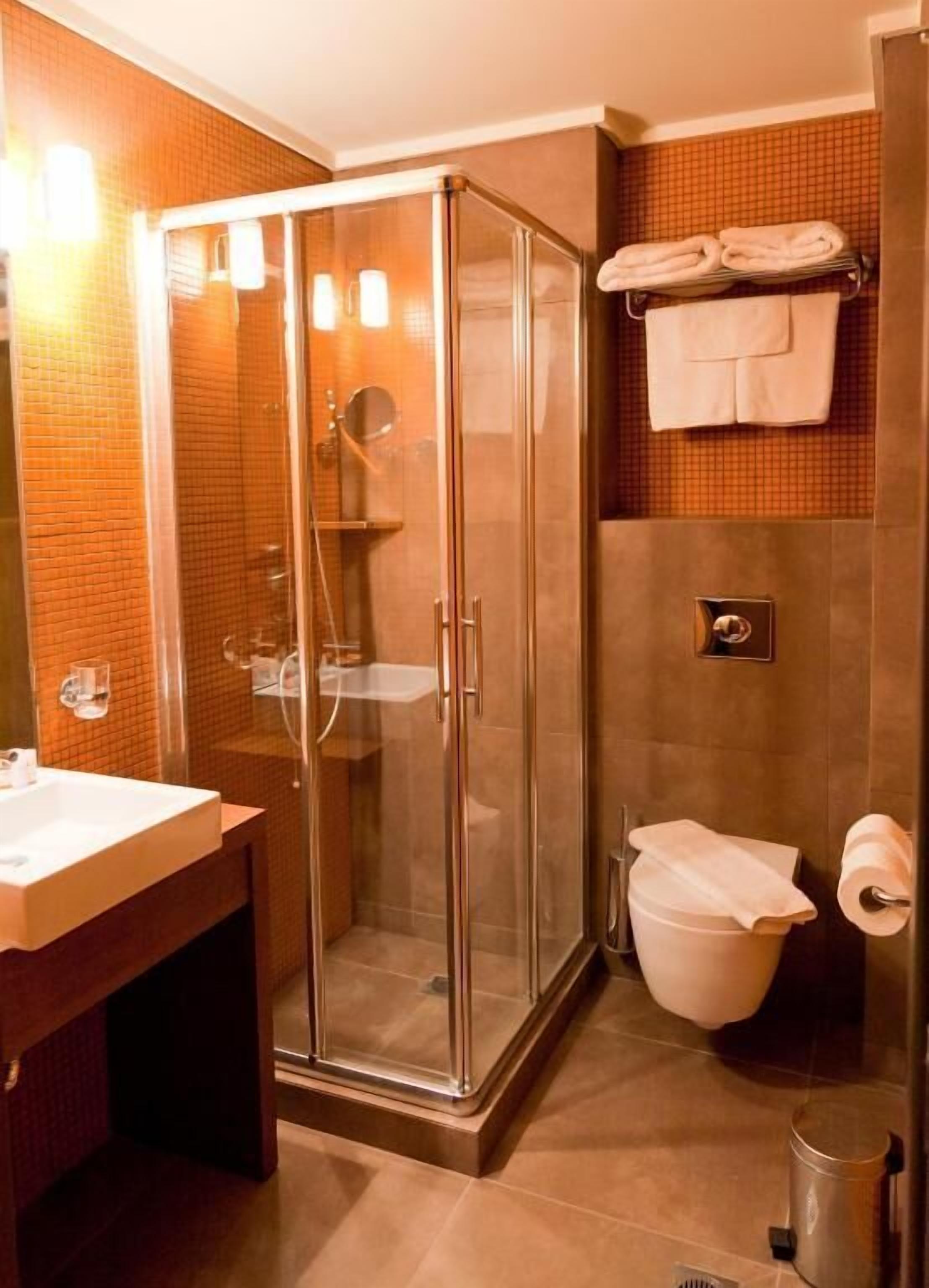 Un baño moderno con ducha de vidrio, lavamanos e inodoro.