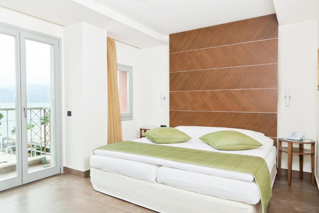 A bedroom with a bed, a wooden headboard, a small bedside table, and a view through a glass door.