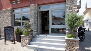 A restaurant with stone pillars, a signboard, and a motorcycle parked outside.