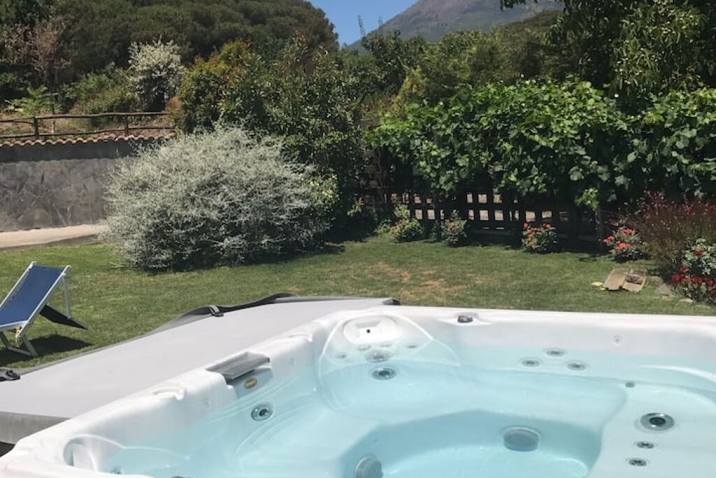 Ein Whirlpool in einem Garten mit Holzzaun, einem Stuhl und üppiger Bepflanzung.