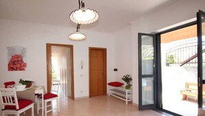 Un'ampia stanza con zona pranzo, una scala e una porta scorrevole in vetro che dà su uno spazio all'aperto.