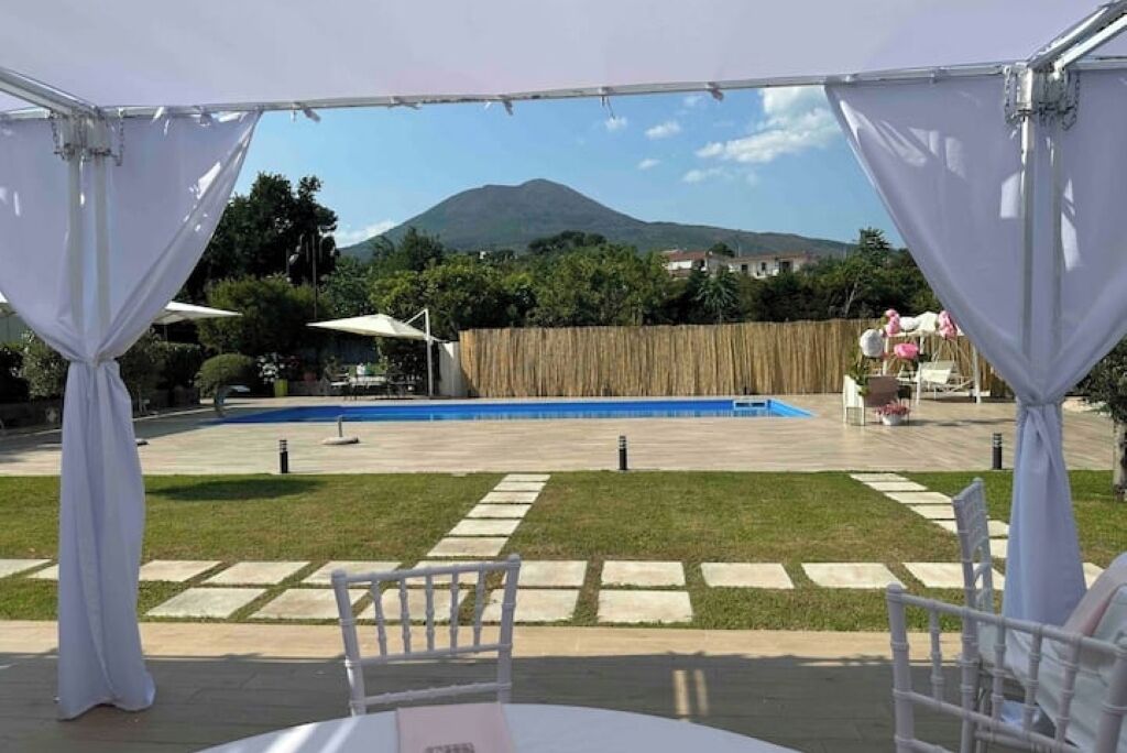 En udendørs terrasse med pool, hvide stole og udsigt til et bjerg.