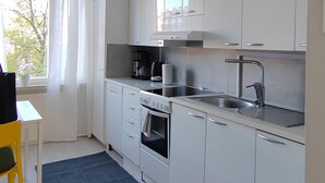 A modern kitchen with white cabinets, a built-in oven, a sink, and a coffee maker. - Kotimaailma KotikolmioVesijk 3622 (Lahti)