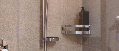 A modern shower with a handheld showerhead, a wall-mounted soap dispenser, and a chrome faucet.
