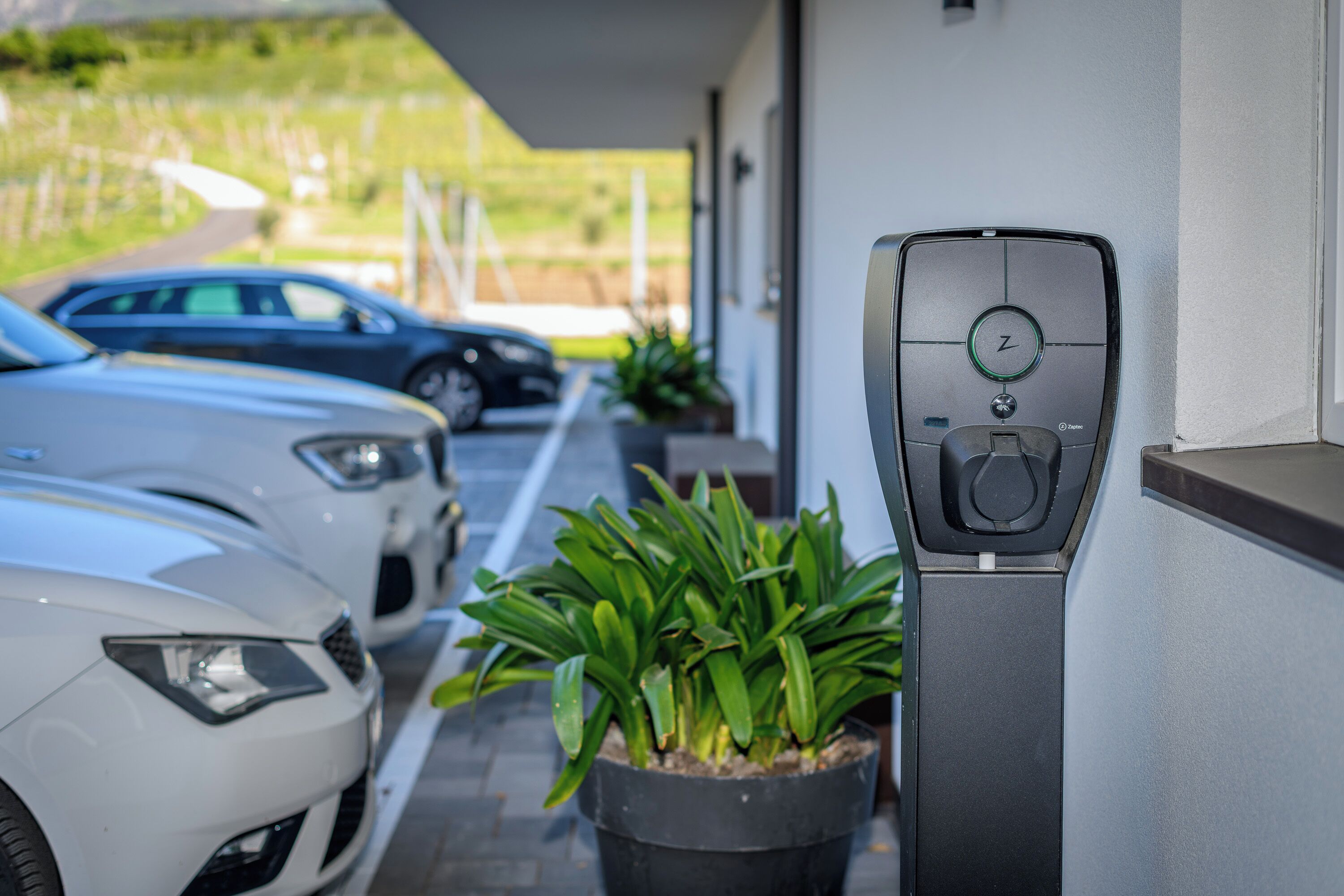 A parking area with electric vehicle charging stations, a potted plant, and a building entrance.
