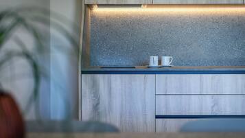 A kitchen with wooden cabinets, a speckled backsplash, and two white cups on a blue countertop.