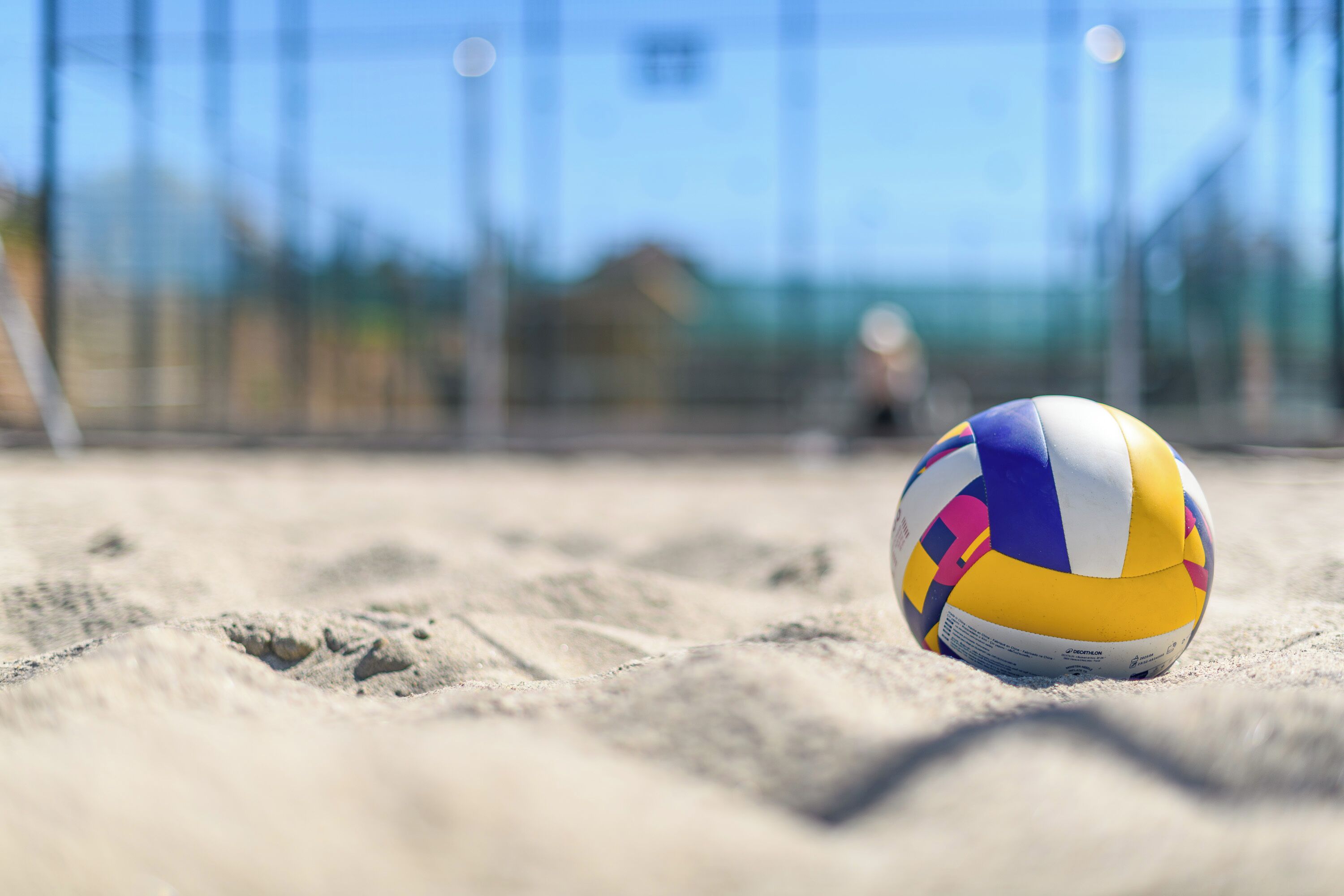 Un voleibol sobre arena, con un fondo desenfocado.