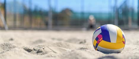 A volleyball on a sandy surface with a blurred background.
