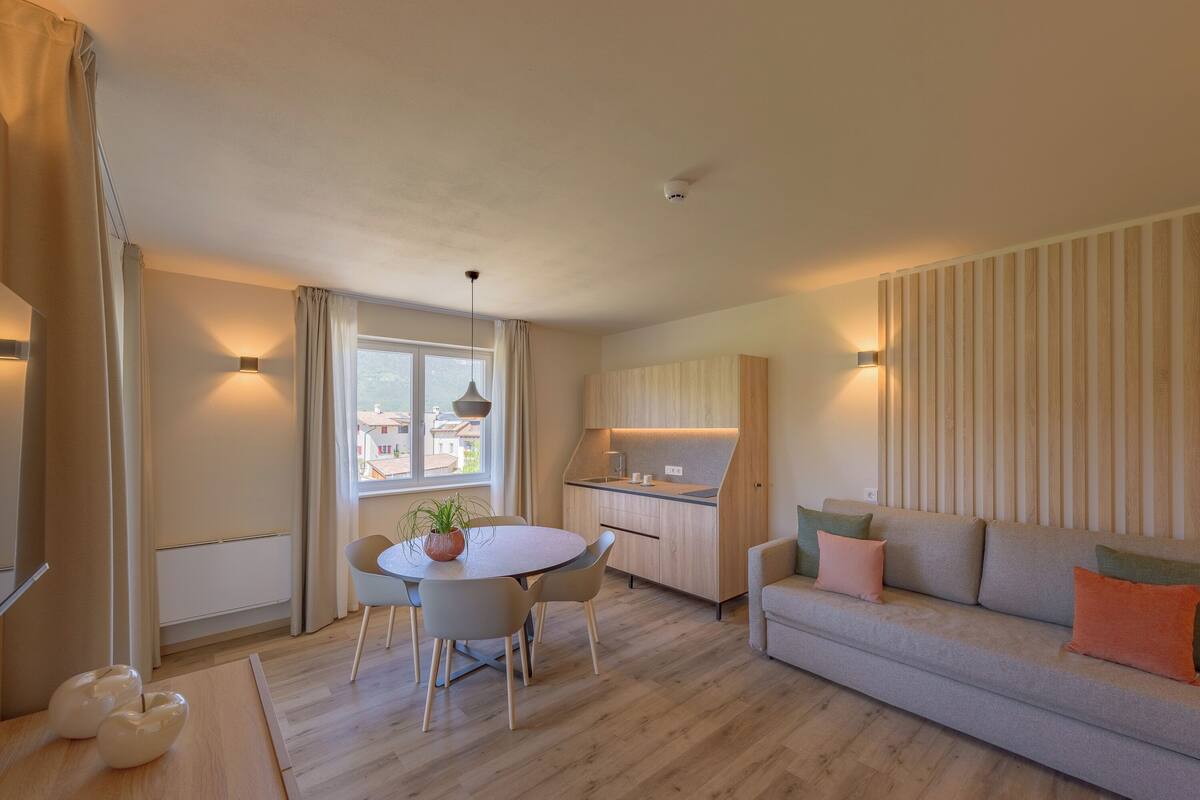 A modern living room with a sofa, dining table, and kitchen area.