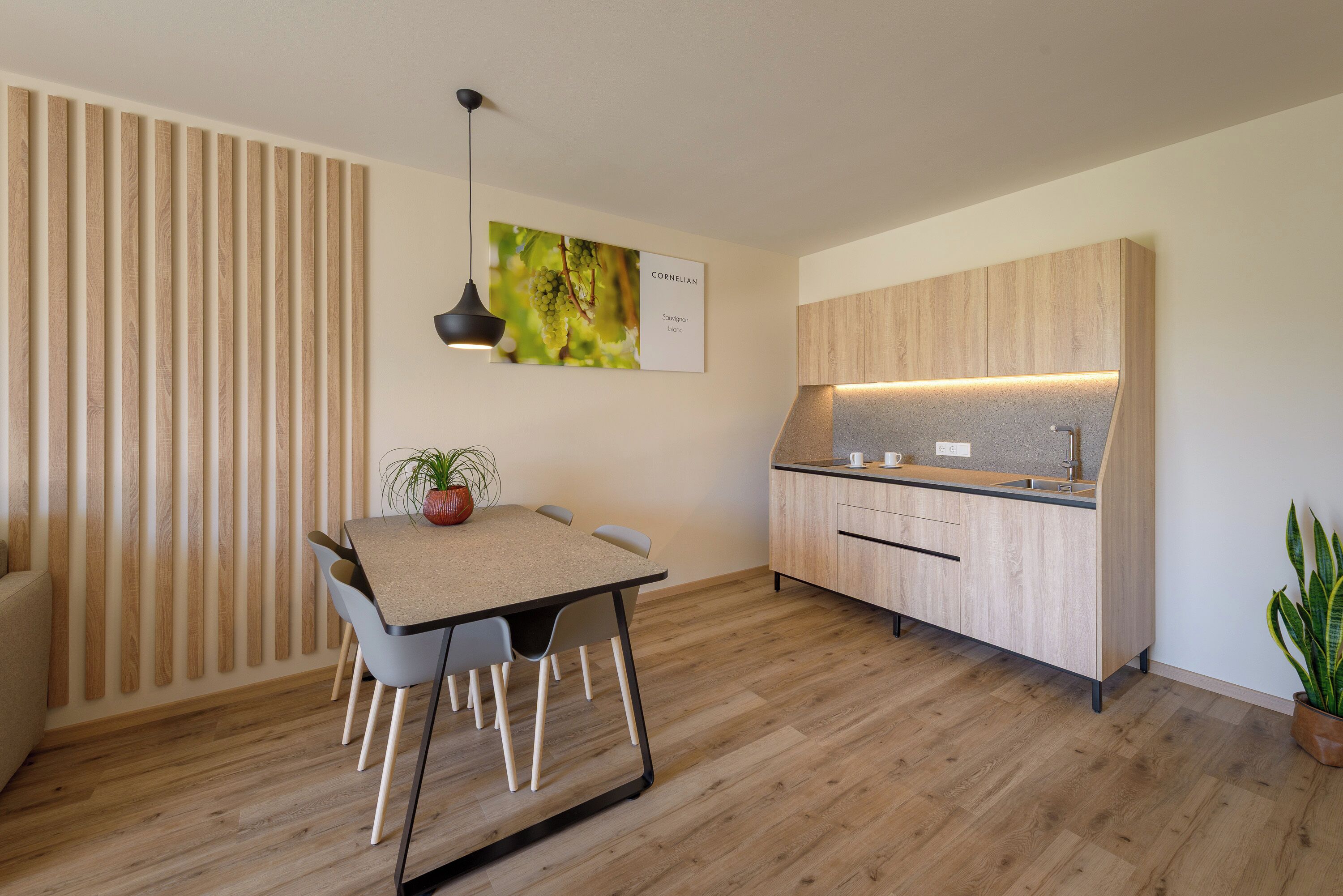 A modern kitchen with wooden cabinets, a dining table with chairs, and a pendant light.