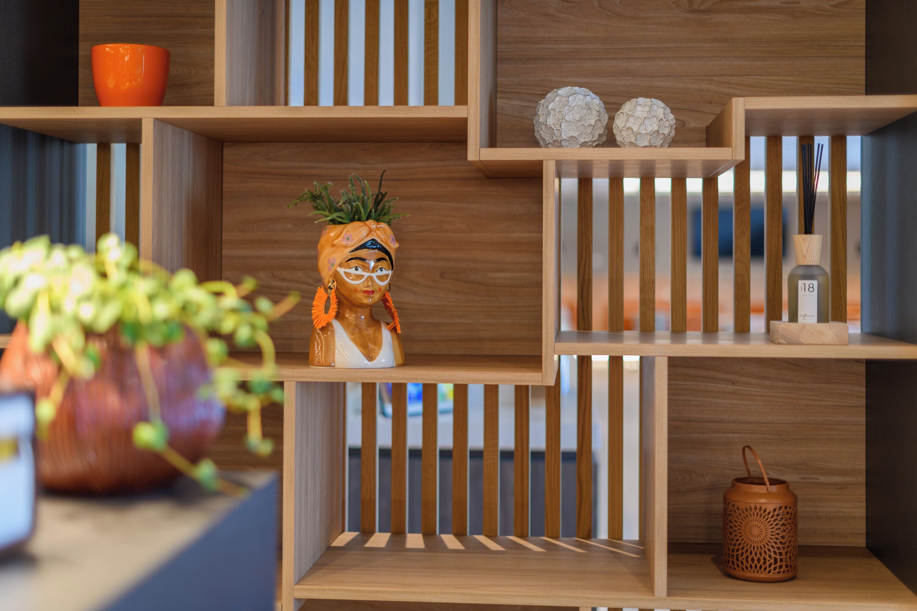 Una scaffalatura in legno con diversi oggetti decorativi, tra cui una pianta, una figurina e un portacandele.