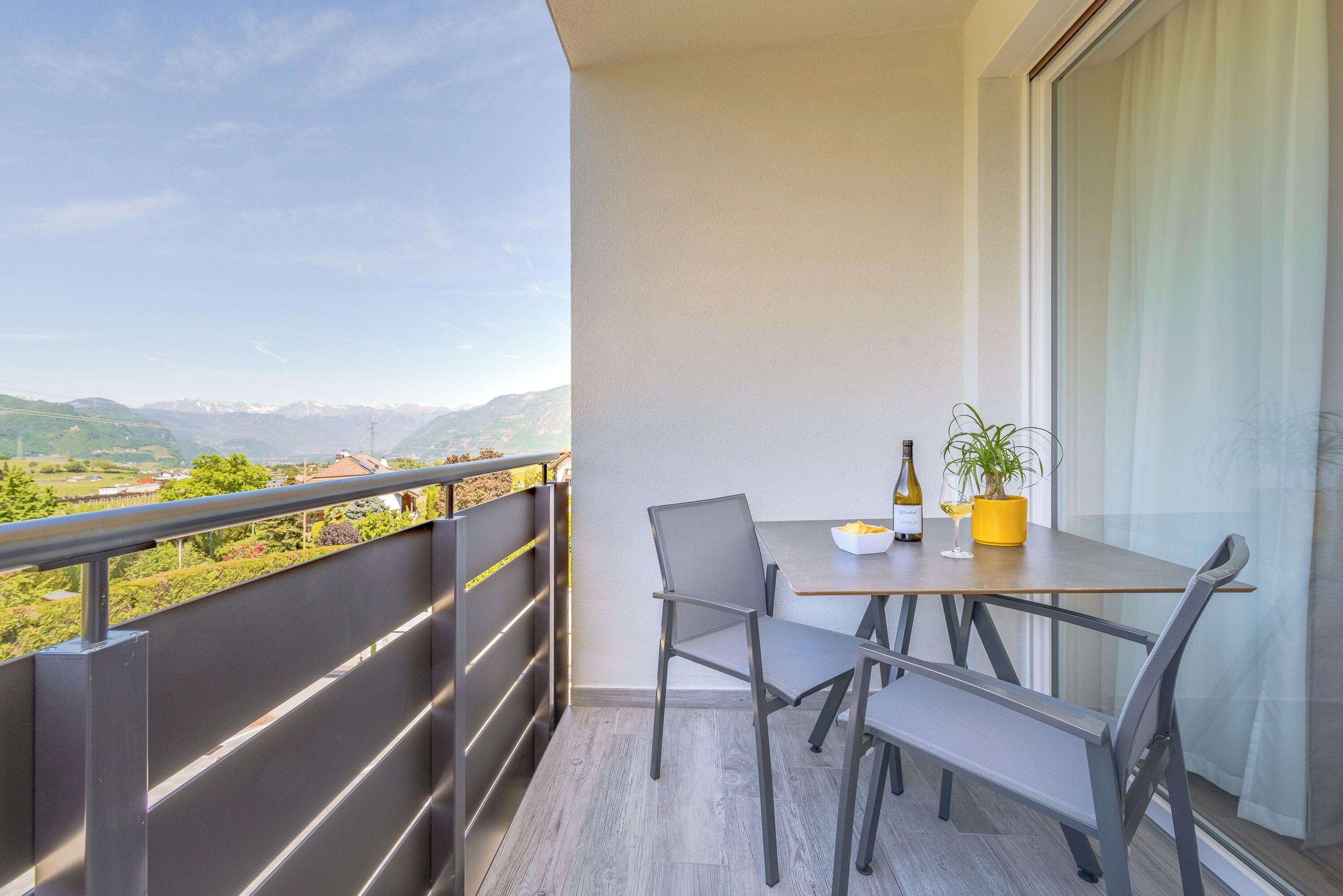A balcony with a table, chairs, a bottle, and a plant.