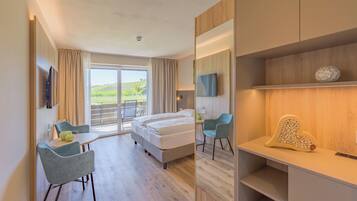 Quarto de hotel moderno com cama, escrivaninha, cadeira, televisão e vista para o exterior.