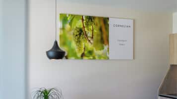 Une enseigne fixée au mur, portant l’inscription « CORNELIAN Sauvignon Blanc », avec un arrière-plan flou de raisins verts.