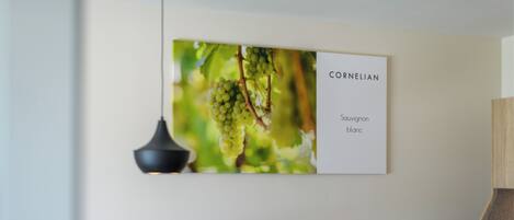 A wall-mounted sign with the text 'CORNELIAN Sauvignon Blanc' and a blurred background of green grapes.