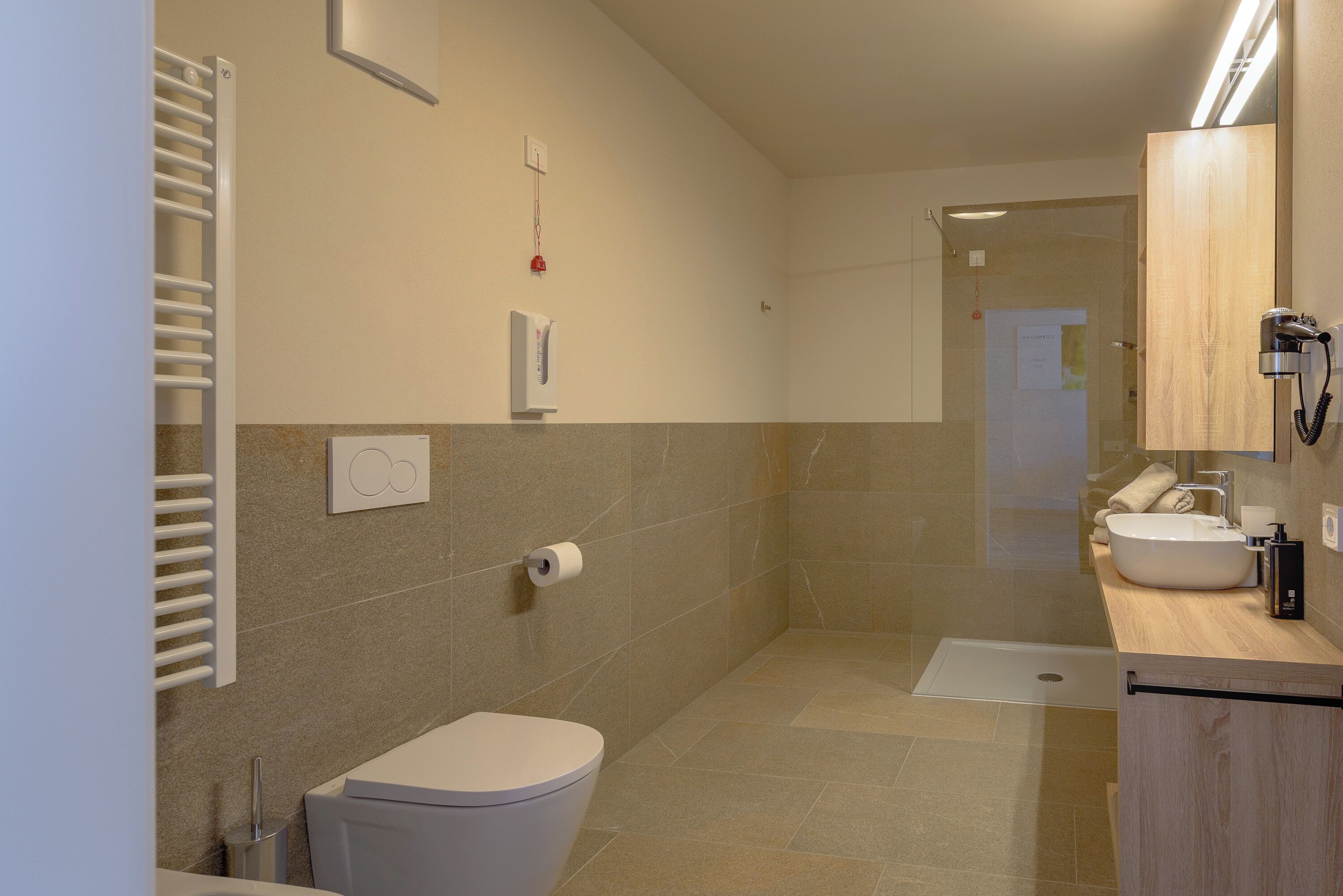 Un baño moderno con inodoro, lavamanos, ducha y toallero.