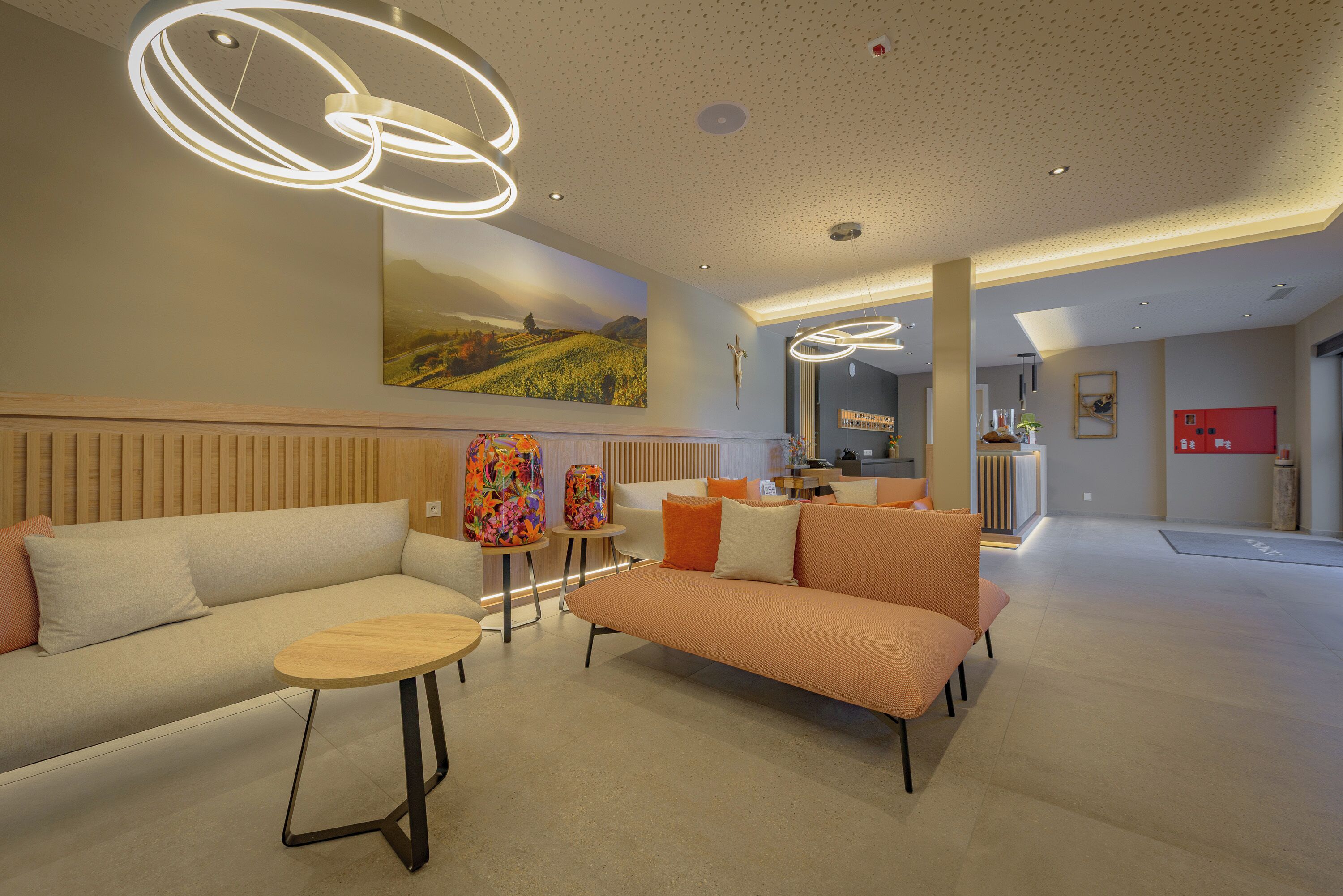 A modern lobby with a sofa, round tables, and a large painting on the wall.
