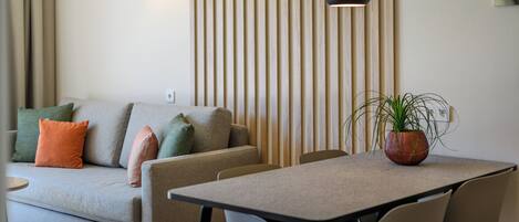 A modern living room with a sofa, a dining table, and a potted plant.