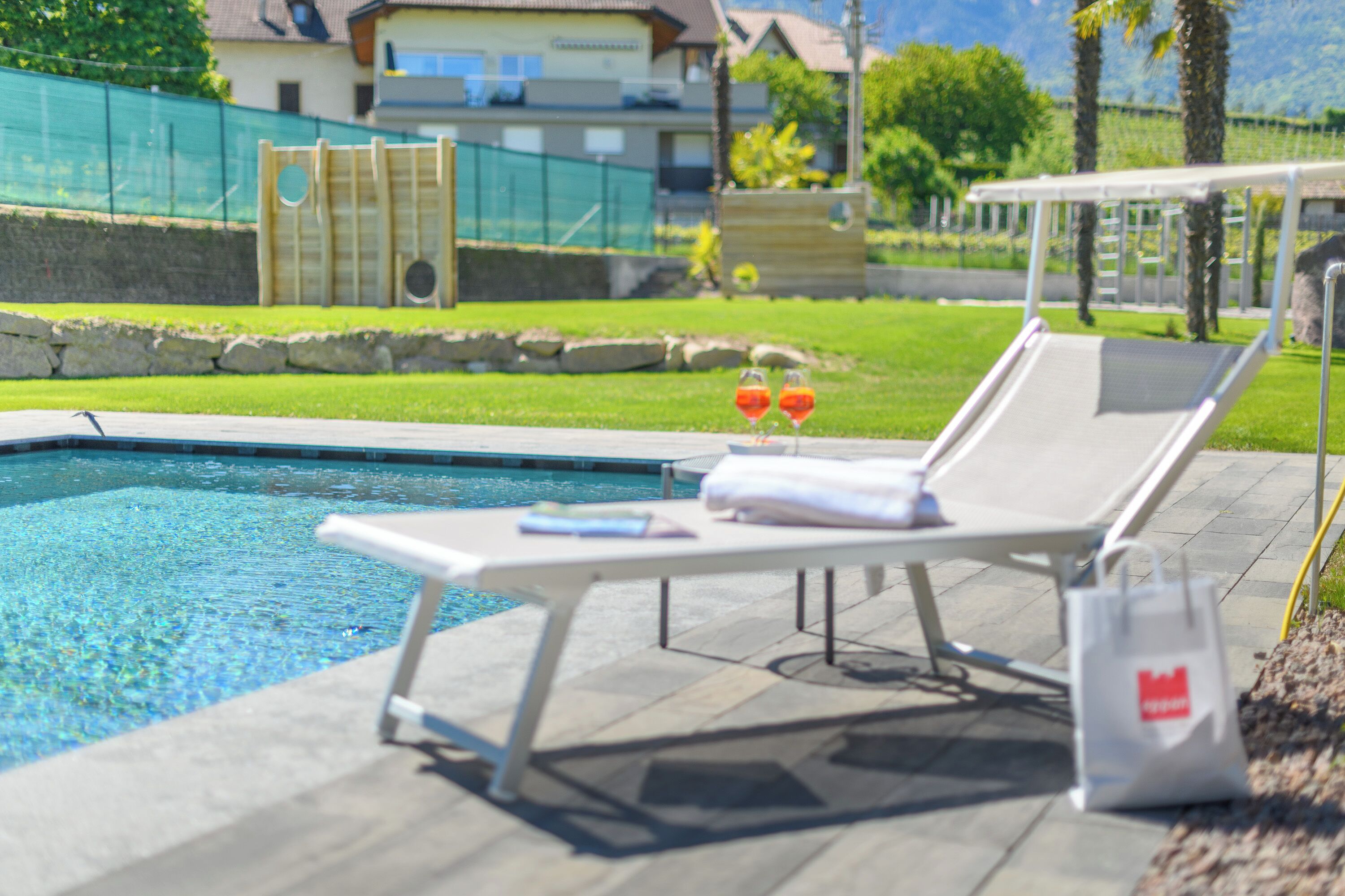 Un espace aménagé au bord de la piscine, avec des chaises longues, une table et un sac.