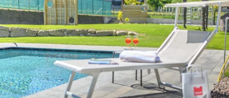 Un espace aménagé au bord de la piscine, avec des chaises longues, une table et un sac.