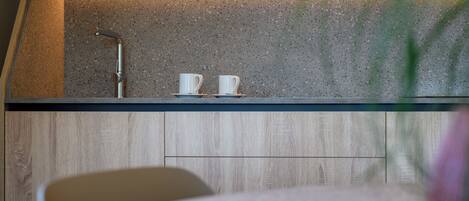 A kitchen with a countertop, two white cups, and a faucet.