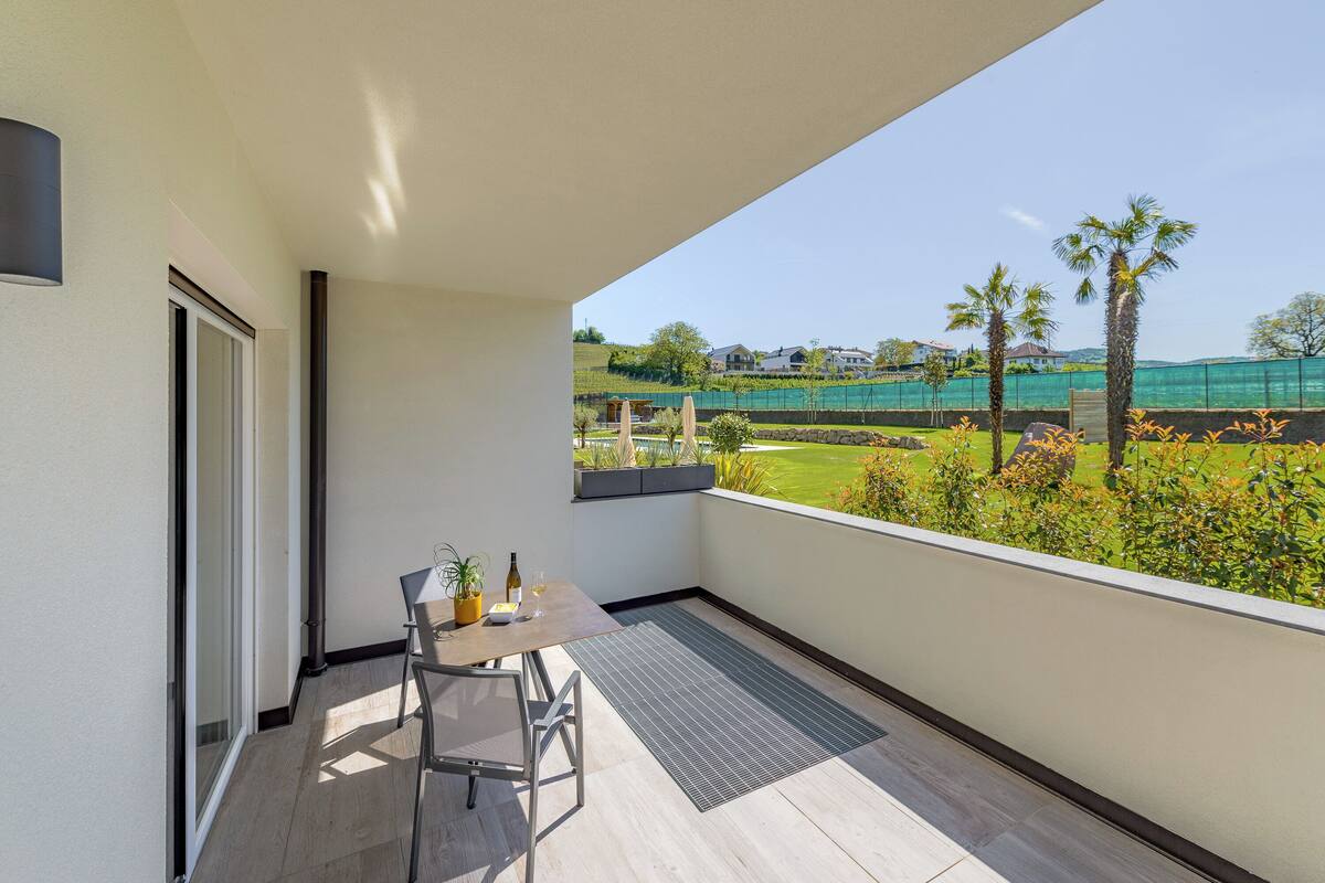 A balcony with a table, chairs, and a view of a golf course.
