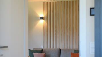 Une pièce avec un canapé, un luminaire fixé au mur et un mur recouvert de lambris en bois.