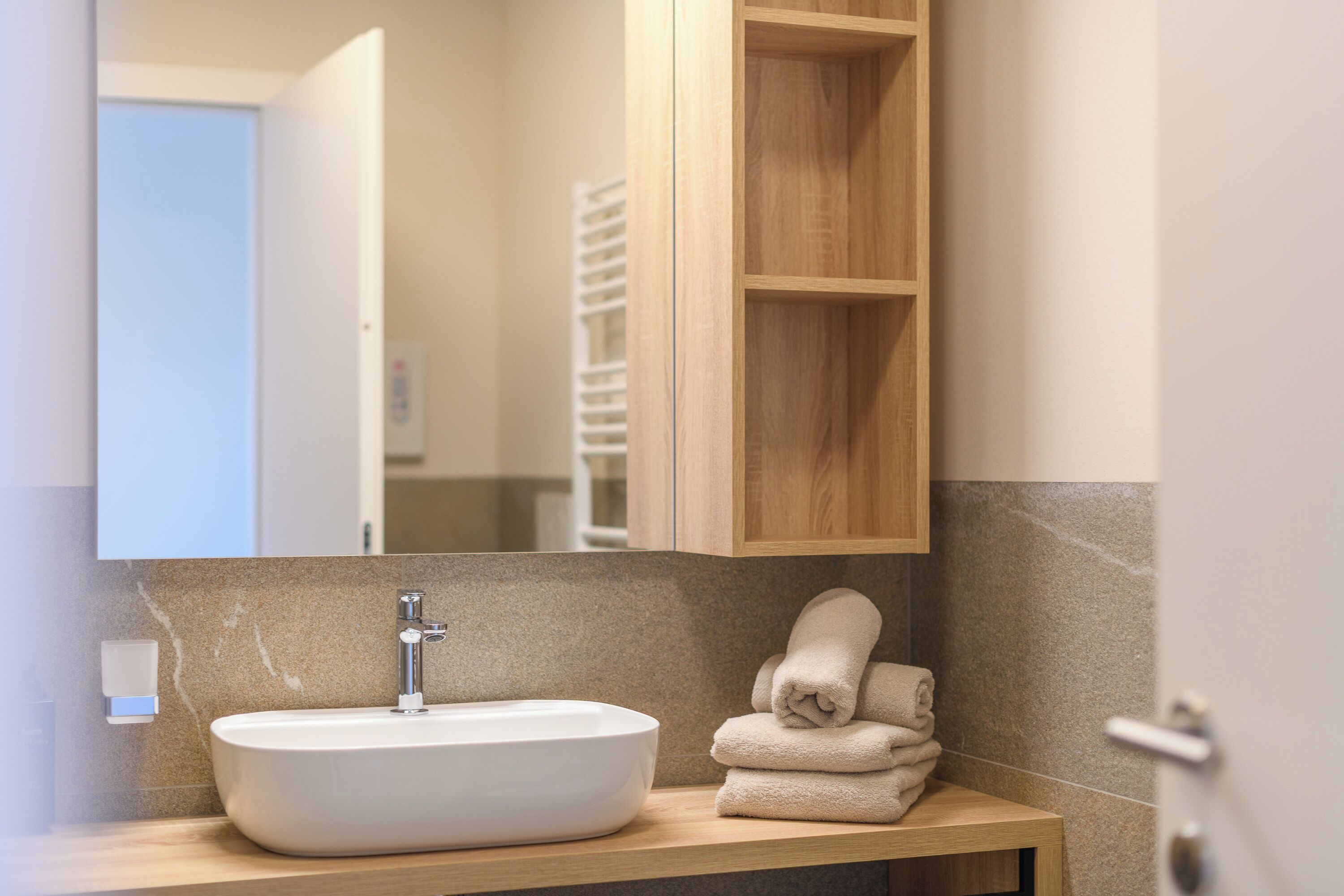 Une salle de bain avec un lavabo blanc, un meuble-lavabo en bois et un miroir.