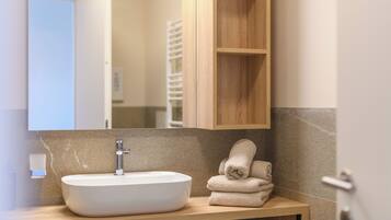 A bathroom with a white sink, wooden vanity, and a mirror.
