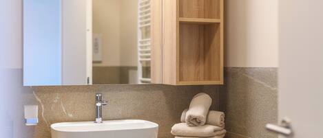 Une salle de bain avec un lavabo blanc, un meuble-lavabo en bois et un miroir.