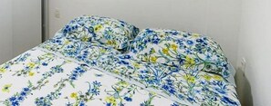 A bed with a floral bedspread and pillows. - Beira Mar C Piscina e Area Gourmet 113D (Ipojuca)